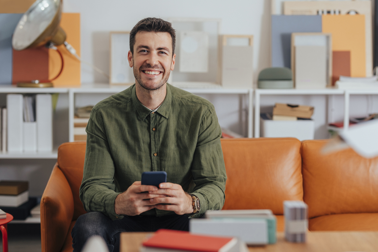 Happy young businessman texting on social media while sitting in his comfortable office