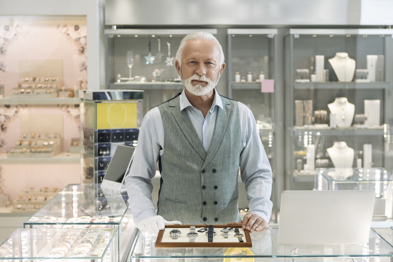 Senior man in jewelry store selling luxury watches looking at camera